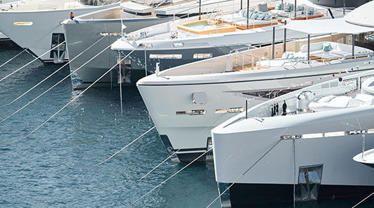 Luxury yachts moored side-by-side in Monaco harbour, reflecting the Monaco residence lifestyle often associated with Monaco residency.