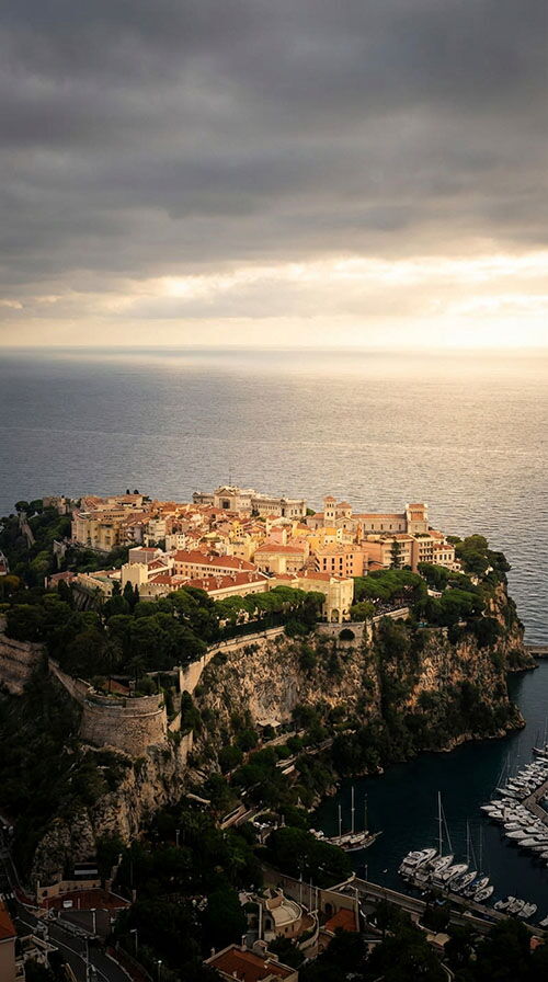 Aerial view of Monaco-Ville on The Rock overlooking the Mediterranean at sunset, used on the Monaco residency application requirements page.