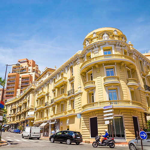Street view in Monaco with classic residential buildings, traffic and pedestrians, representing Monaco residence and residency in Monaco.